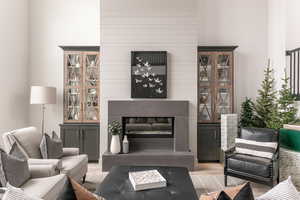 Living room featuring light wood-type flooring, a towering ceiling, and a large fireplace