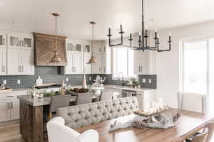 Kitchen featuring tasteful backsplash, white cabinets, decorative light fixtures, and a kitchen island