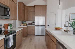 Kitchen with tasteful backsplash, sink, light hardwood / wood-style flooring, hanging light fixtures, and appliances with stainless steel finishes