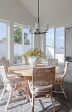 Dining room featuring a wealth of natural light, a chandelier, and vaulted ceiling