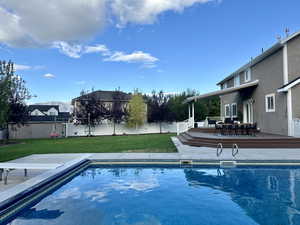 View of pool with a lawn, a diving board, and decks