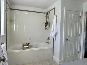 Primary Bathroom featuring jetted bathtub / shower combination and tiled floors