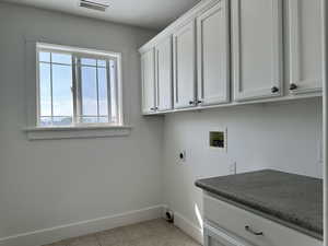 Laundry with washer hookup, cabinets, light tiled floors, and hookup for an electric dryer