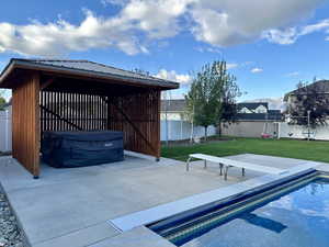 View of pool featuring a hot tub, a lawn, and a patio area