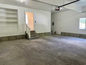 Garage featuring electric panel built in shelves, extra storage space and a man door