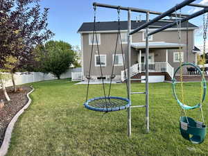 Rear view of property with a lawn, swing set, walk out basement, terrace decking and patio