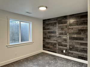 Fifth bedroom featuring a wooden accent wall and carpet floors