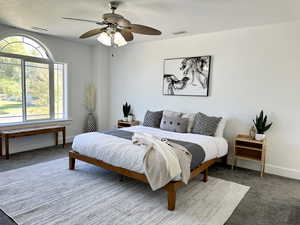 Primary Bedroom featuring large window, dark carpet and ceiling fan