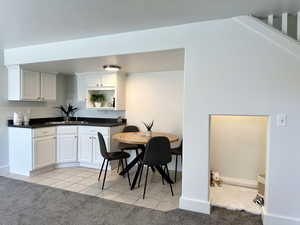 Kitchen featuring light carpet, white cabinetry, and sink