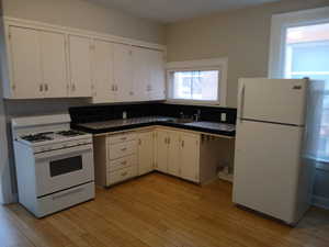 Kitchen with white appliances, white cabinets, tile countertops, and light wood finished floors