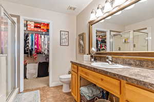 Bathroom with tile patterned flooring, a shower with shower door, toilet, and vanity