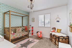 Carpeted bedroom with a nursery area and an inviting chandelier