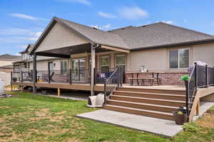 Rear view of house featuring a wooden deck, a yard, and a patio area