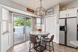 Dining room with lofted ceiling, a notable chandelier, and light tile patterned flooring