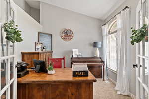 Carpeted office space with lofted ceiling and a healthy amount of sunlight