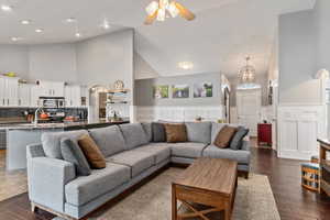 Living room featuring a towering ceiling, dark hardwood / wood-style flooring, ceiling fan with notable chandelier, and sink