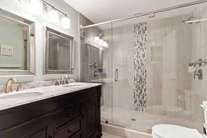 Bathroom with walk in shower, toilet, a textured ceiling, and vanity