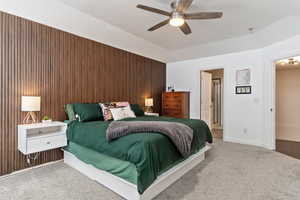 Bedroom featuring wood walls, ceiling fan, and carpet