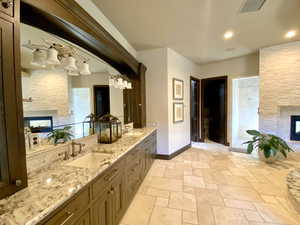 Primary bathroom with vanity, a multi sided fireplace, and a shower