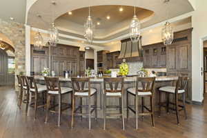 Kitchen featuring a chandelier, premium range hood, arched walkways, and backsplash