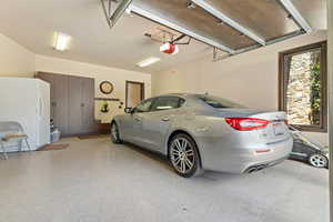 Garage featuring a garage door opener and freestanding refrigerator
