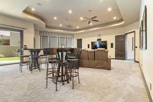 Carpeted dining area featuring recessed lighting, a ceiling fan, a raised ceiling, and baseboards