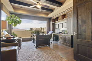 Office area with a ceiling fan, dark wood-style flooring, a wealth of natural light, and a tray ceiling