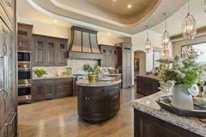 Kitchen with a raised ceiling, arched walkways, a kitchen island, and stainless steel appliances