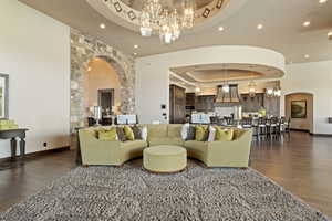 Living room featuring a notable chandelier, recessed lighting, a tray ceiling, and arched walkways