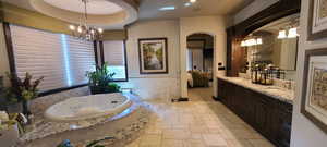 Bathroom featuring a tub, a tray ceiling, and double vanity