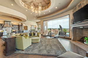 Living area with hardwood / wood-style floors, a notable chandelier, a fireplace, and a tray ceiling