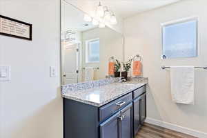 Bathroom featuring vanity and laminate floors with separate water closet.