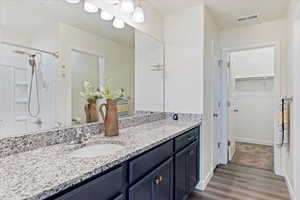 Bathroom with vanity, laminate flooring, and walk in shower.