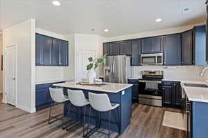 Kitchen featuring appliances with stainless steel finishes, farmhouse sink, laminate flooring, a kitchen breakfast bar, and productivity desk.