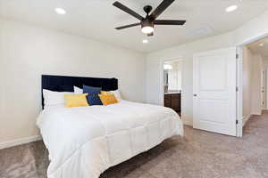 Carpeted bedroom featuring ensuite bath and ceiling fan.