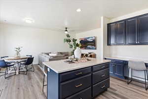 Kitchen featuring appliances with stainless steel finishes, farmhouse sink, laminate flooring, a kitchen breakfast bar, and productivity desk.