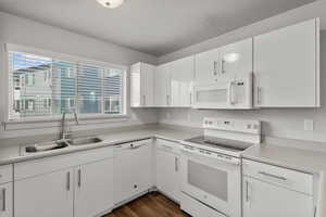 Kitchen featuring white cabinetry, white appliances, plenty of natural light, and sink