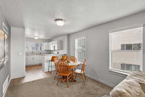 Dining room with a wealth of natural light, light hardwood / wood-style floors, a textured ceiling, and sink