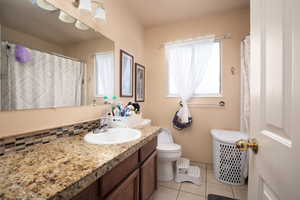 Bathroom featuring toilet, tile patterned floors, vanity, decorative backsplash, and a shower with curtain