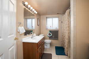 Bathroom featuring vanity, toilet, curtained shower, and tile patterned flooring