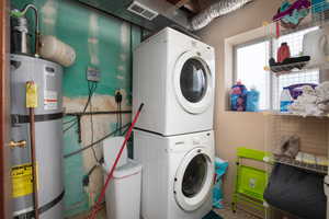 Clothes washing area featuring stacked washer and dryer and secured water heater