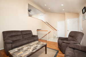 Living room with light wood-type flooring, ceiling fan, and vaulted ceiling