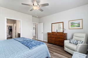 Bedroom with a spacious closet, a closet, hardwood / wood-style floors, ensuite bath, and ceiling fan