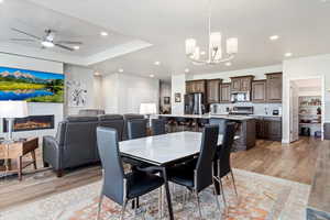 Dining room with light wood-type flooring and ceiling fan with notable chandelier