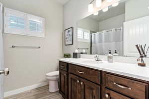 Bathroom with a shower with shower curtain, vanity, toilet, and hardwood / wood-style flooring