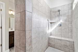 Bathroom featuring tile patterned floors, a tile shower, and vanity