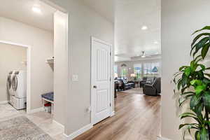 Corridor featuring a textured ceiling, light hardwood / wood-style flooring, and independent washer and dryer