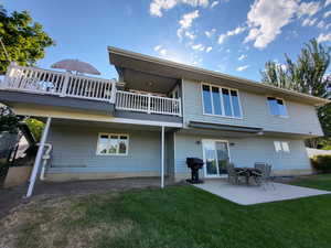 Rear view of property featuring a yard, a patio, and a balcony