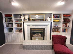 Living room featuring a textured ceiling, a tile fireplace, and carpet floors