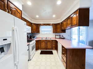 Kitchen with a wealth of natural light, crown molding, sink, and white appliances